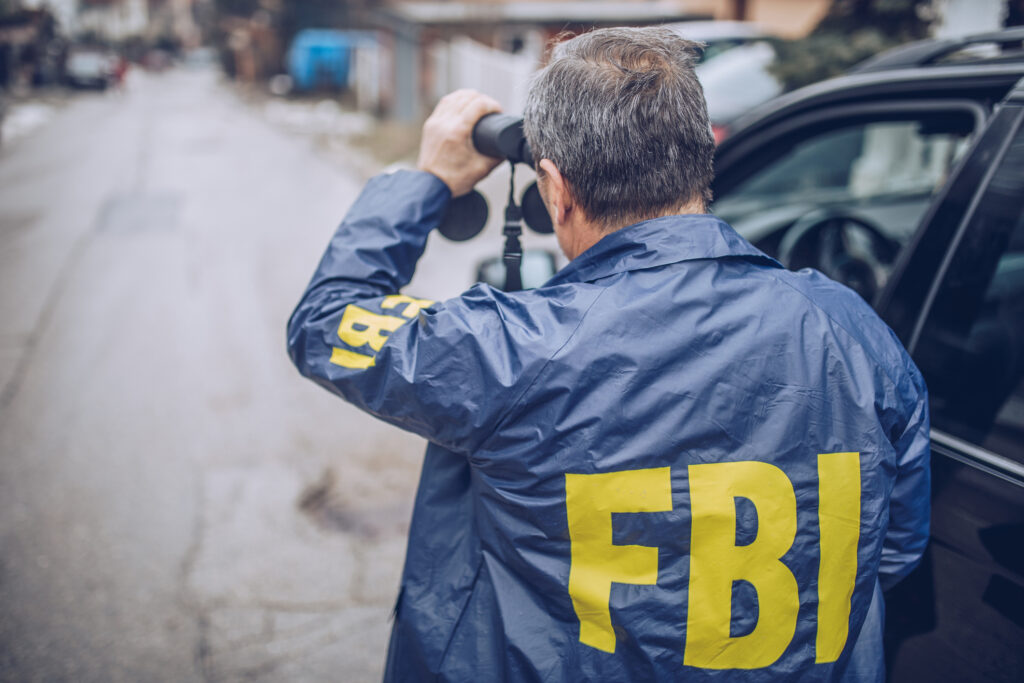 An FBI agent uses binoculars for observation