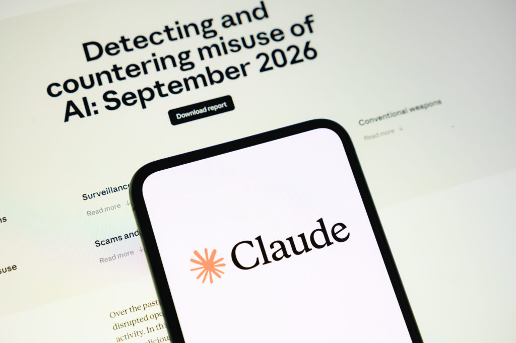 The Claude logo is displayed on a smartphone screen with the webpage of the company's report on malicious use in the background in Creteil, France, on September 11, 2026.